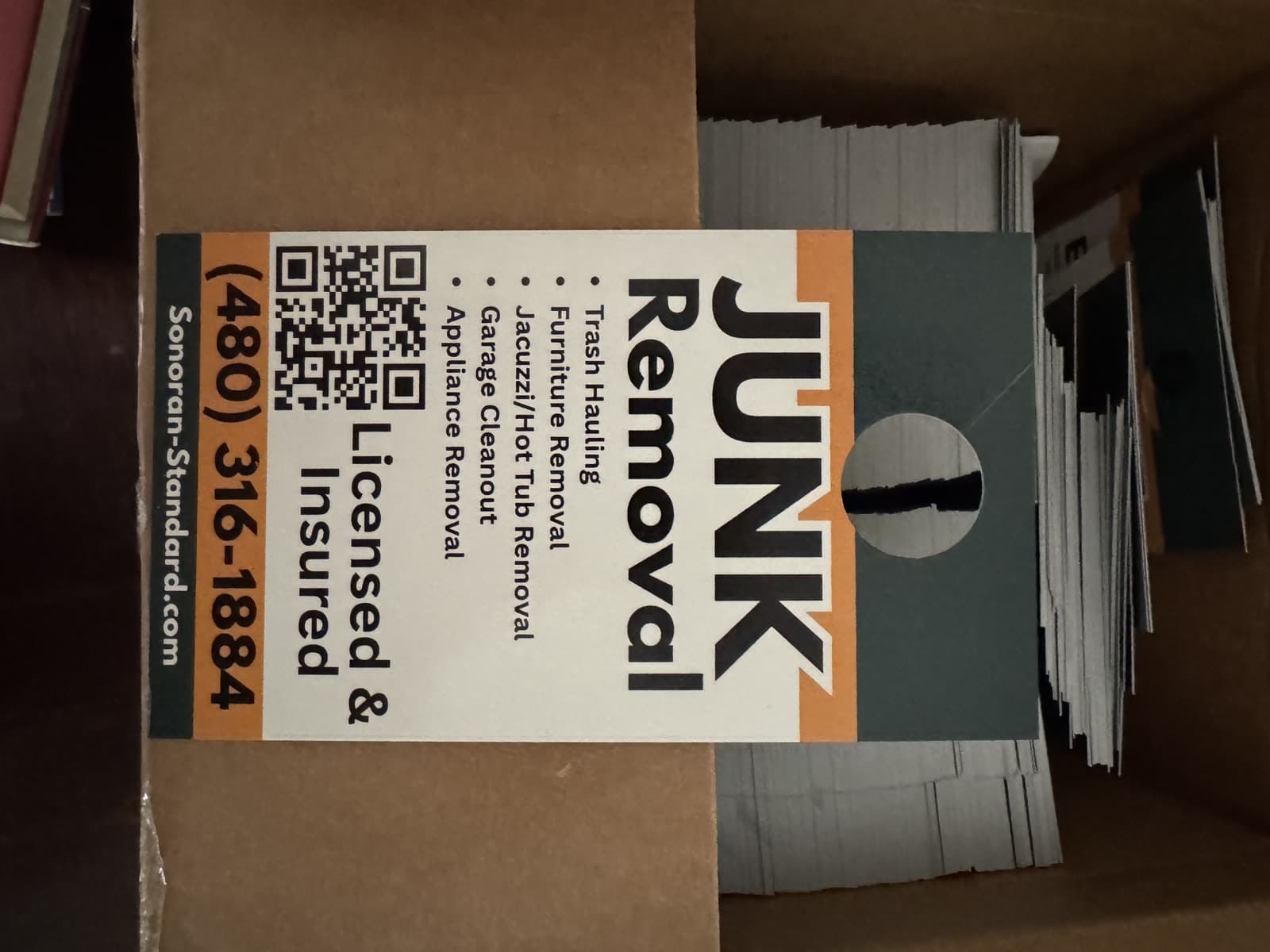 Box of Sonoran Standard junk removal door hangers, front side
