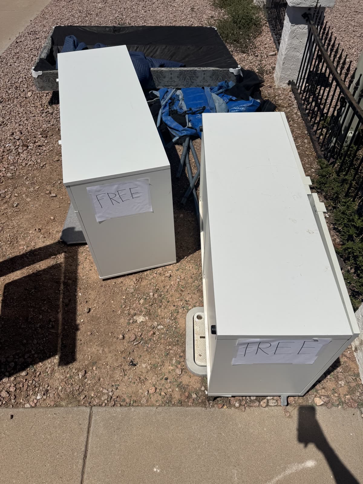 Two white cabinets with handwritten free signs still at the curb a week later, picked up on a furniture removal job