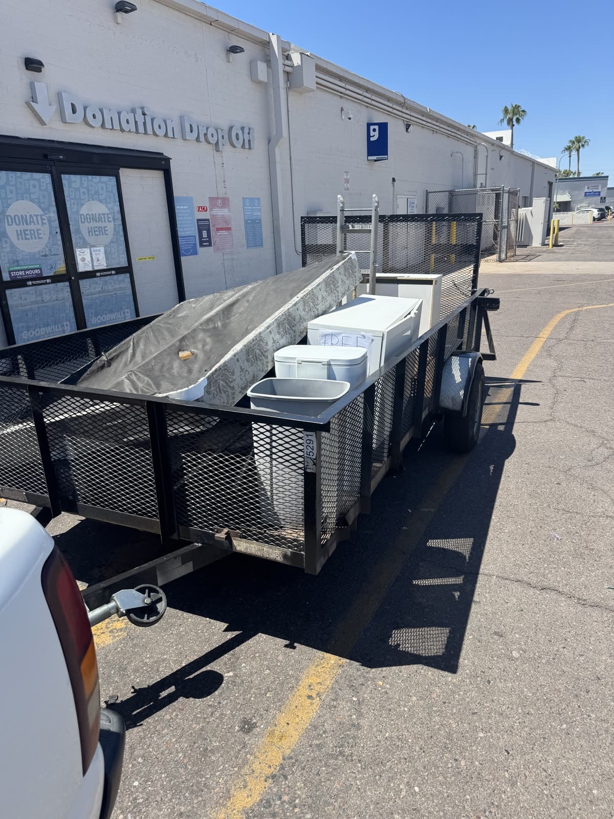 Sonoran Standard trailer at the Goodwill donation drop off with a mattress, cabinet, and cooler on it