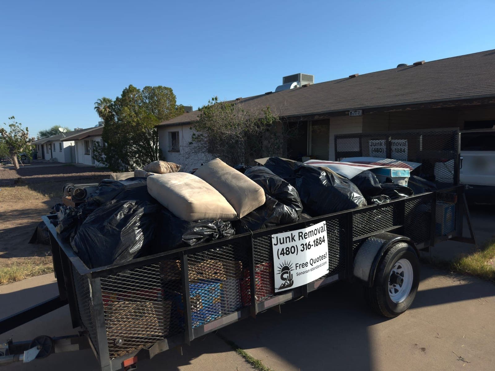 Trailer loaded with bags and cushions in the driveway