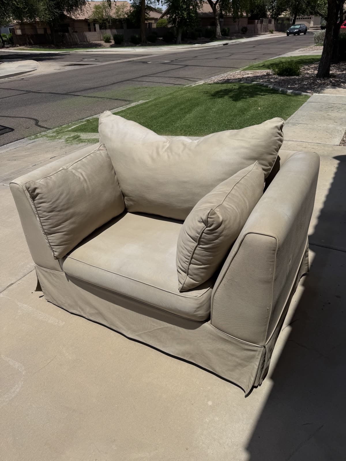 Oversized beige armchair at the curb on a Mesa street ready for pickup