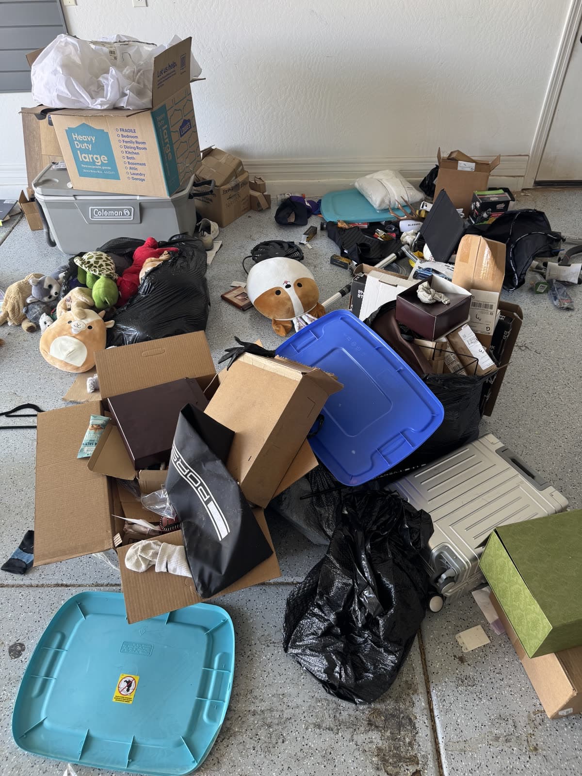 Garage floor covered in boxes, bags, and household items before a cleanout