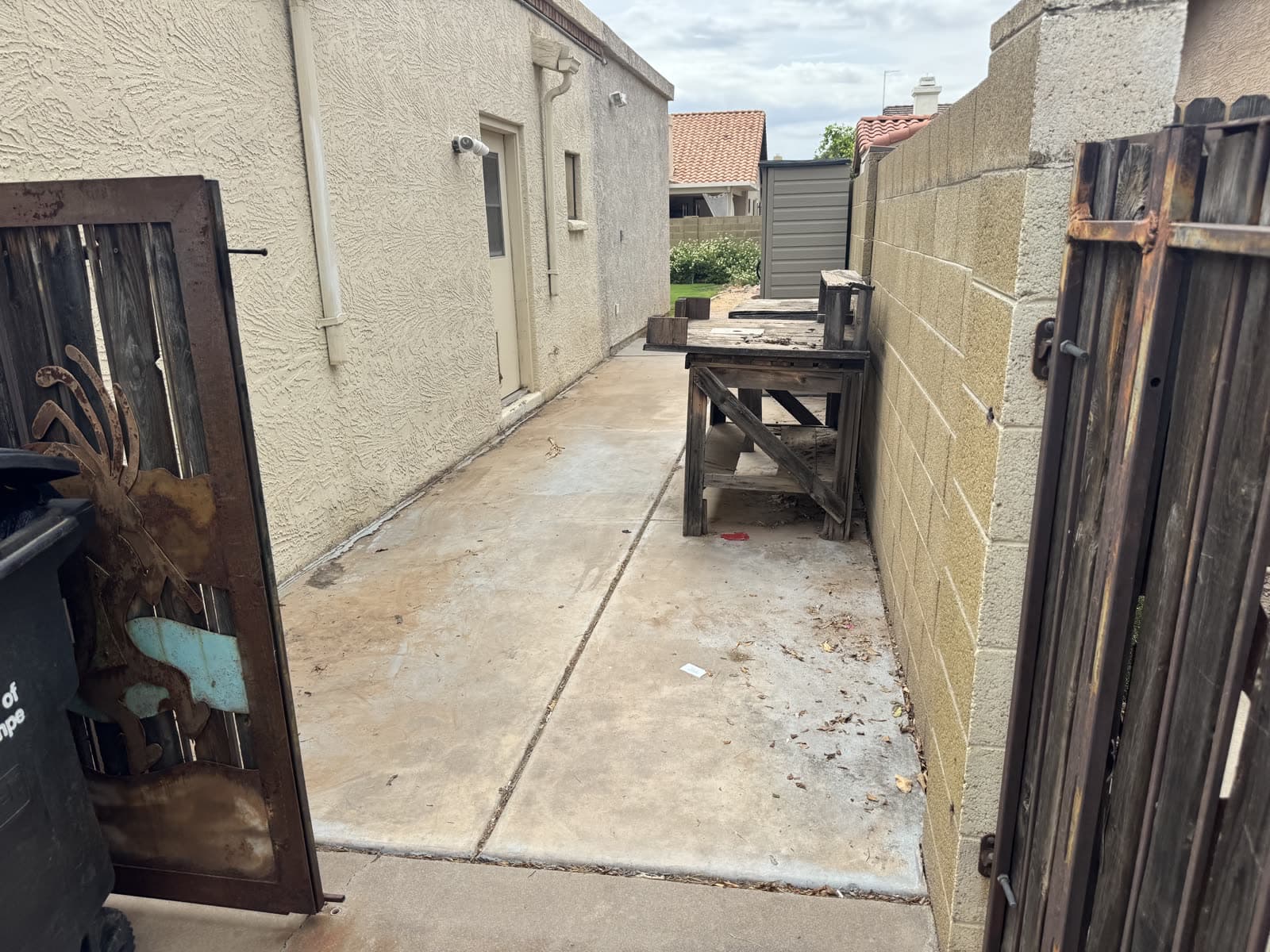 The same side yard cleared after the junk removal cleanout, gate open, work bench left in place